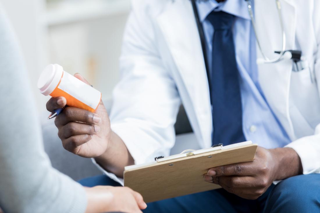 Doctor with list of ADHD medication holding prescription bottle.